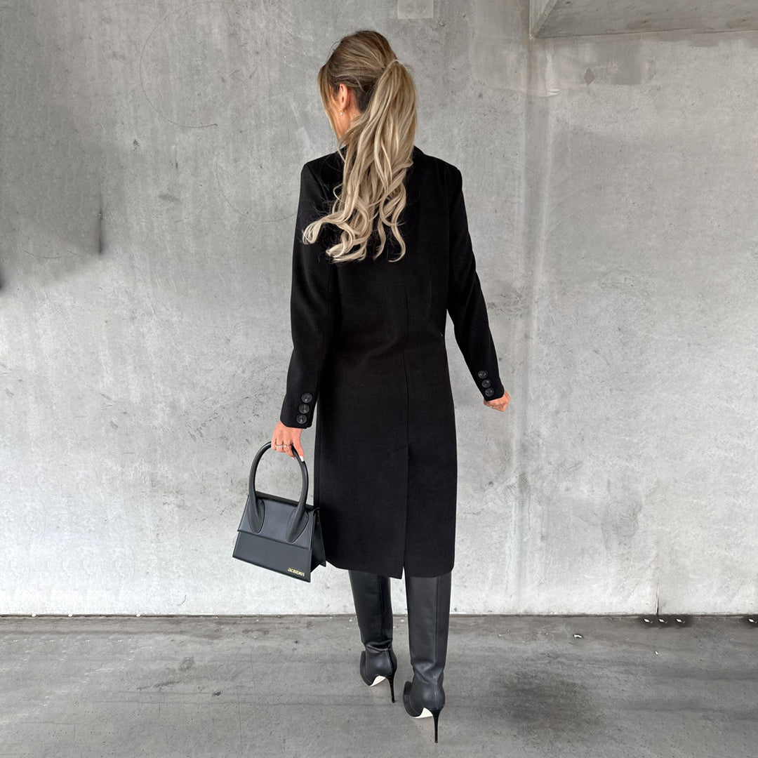 Vrouw in zwarte winterjas, hoge laarzen en met een zwarte handtas. Stijlvolle wintermode, elegante dameskleding, moderne outfit.