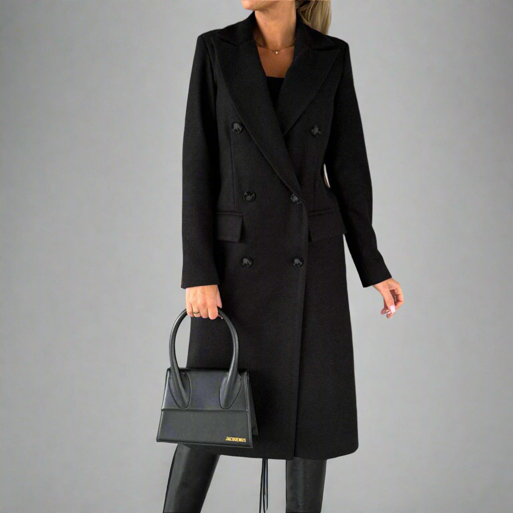 Zwarte winterjas voor dames, dubbele rij knopen, elegante lange mantel, gecombineerd met zwarte handtas en laarzen, modieuze winterkleding.